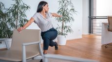 Woman holds back of office chair, twists and lunges