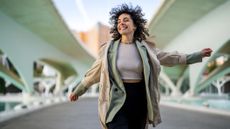 Smiling woman walking outside swinging her arms