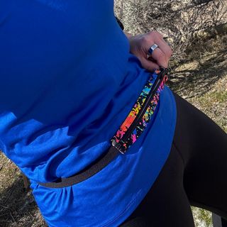 Close up of midrift with thin running belt, the pouch has a splotchy design with flourscent colors