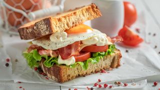 A sandwich with eggs, bacon, tomatoes and lettuce.