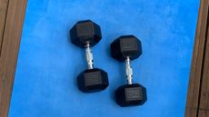 Two dumbbells with black hexagonal heads on blue exercise mat seen from above