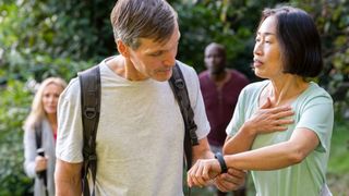 Man viewing the data on a women's fitness tracker while walking