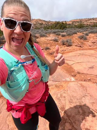 Woman in sportswear giving thumbs up to camera with mouth open and a happy expression